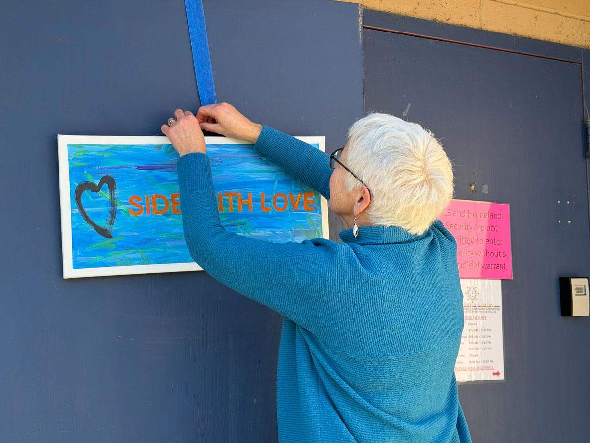 Mary Madsen hangs a sign that says “Side with Love” at Cascade Unitarian Universalist Fellowship church in East Wenatchee.