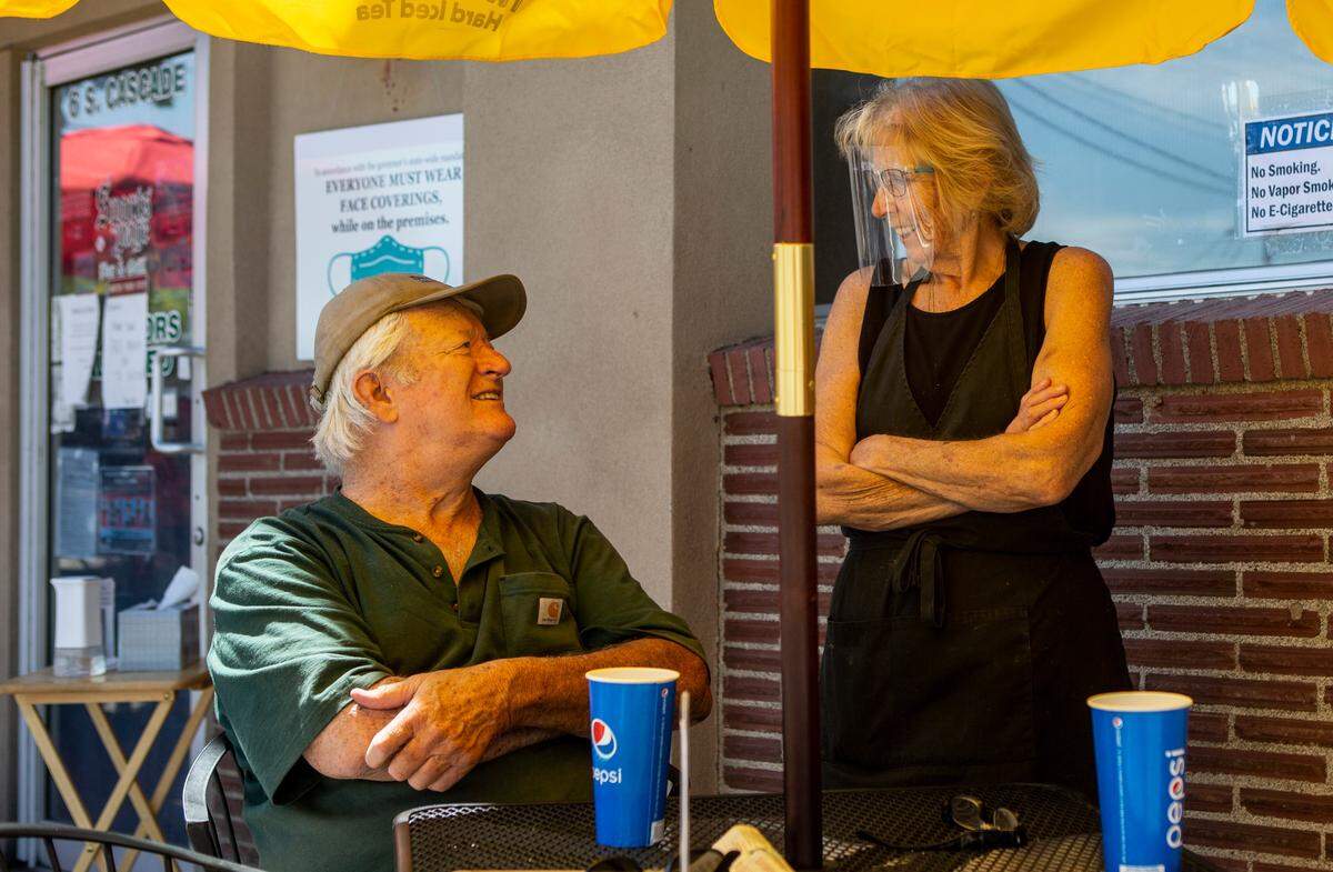 Sports Page Bar & Grill owner Terri Rullman, on right, talks with patrons in the restaurant’s outside seating area along South Cascade Street. Tri-Cities restaurants and bars are making changes, such as increased outdoor seating, to accommodate coronavirus regulations.