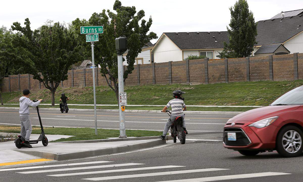 Young riders are passing the site of Tuesday night's fatal collision involving an e-bike rider who collided with an SUV at the intersection of Road 60 Drive and Burns Road near Sageview High School in west Pasco. 