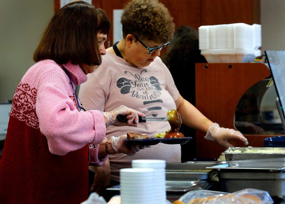 Volunteers fix plates of roast beef meals to serve to senior visitors at the Mid-Columbia Meals on Wheels cafe in Richland.