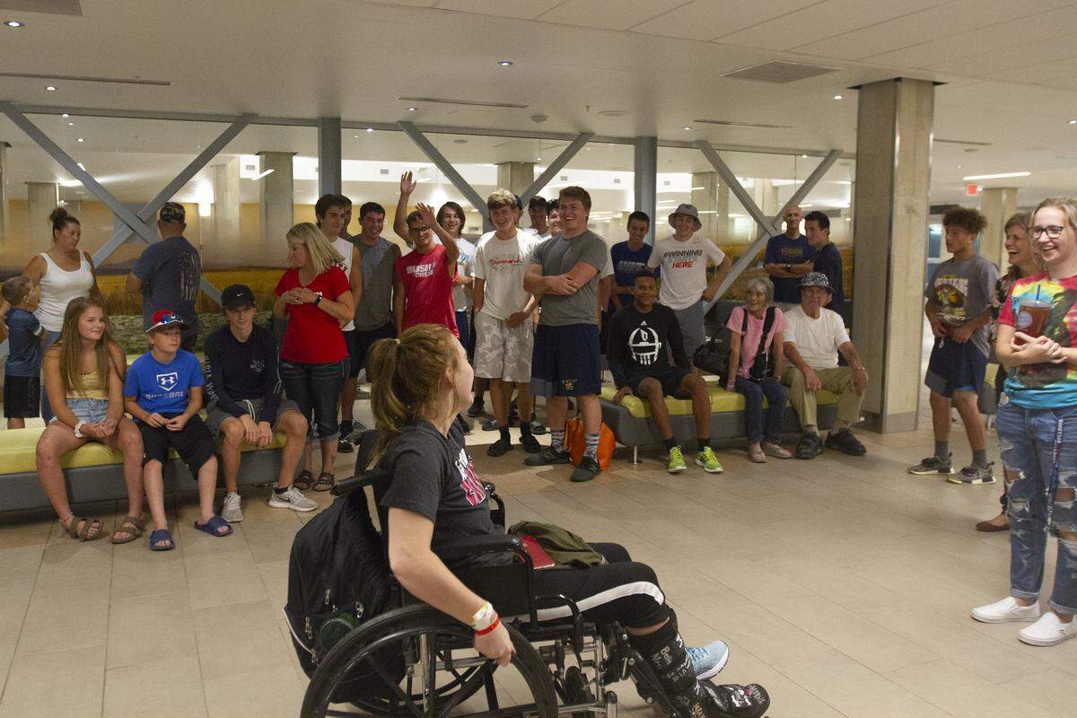 Friends, family and Tri-Cities Prep football team surround and surprise Danika Whitsett as she arrives at Wednesday night at the Tri-Cities Airport in Pasco..