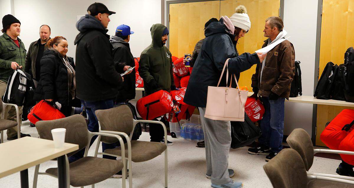 Nearly 30 volunteers carry sleeping bags and backpacks filled with supplies for the homeless as they leave to conduct the annual Point in Time count from a meeting room at the Benton Franklin Health Department in Kennewick.