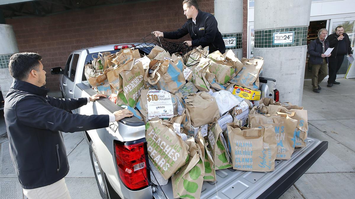 McCurley employees Alejandro Arroyo, left, and Derrick Riley prepare to arrange bags of donated food from Yoke’s Fresh Market customers at the grocery store chain’s location in West Richland. The 17th annual Octoberfest Food Bank Food Drive by southeast Washington McCurley stores and Yoke’s customers collected 58,000 pounds of donated food to benefit local food banks.