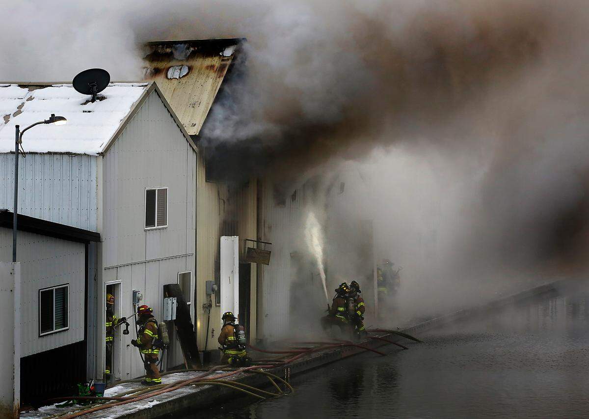 Firefighters from agencies around the Tri-Cities area work from the floating boat docks help stop the spread of a boathouse fire early Wednesday morning at the Clover Island Yacht Club in downtown Kennewick.