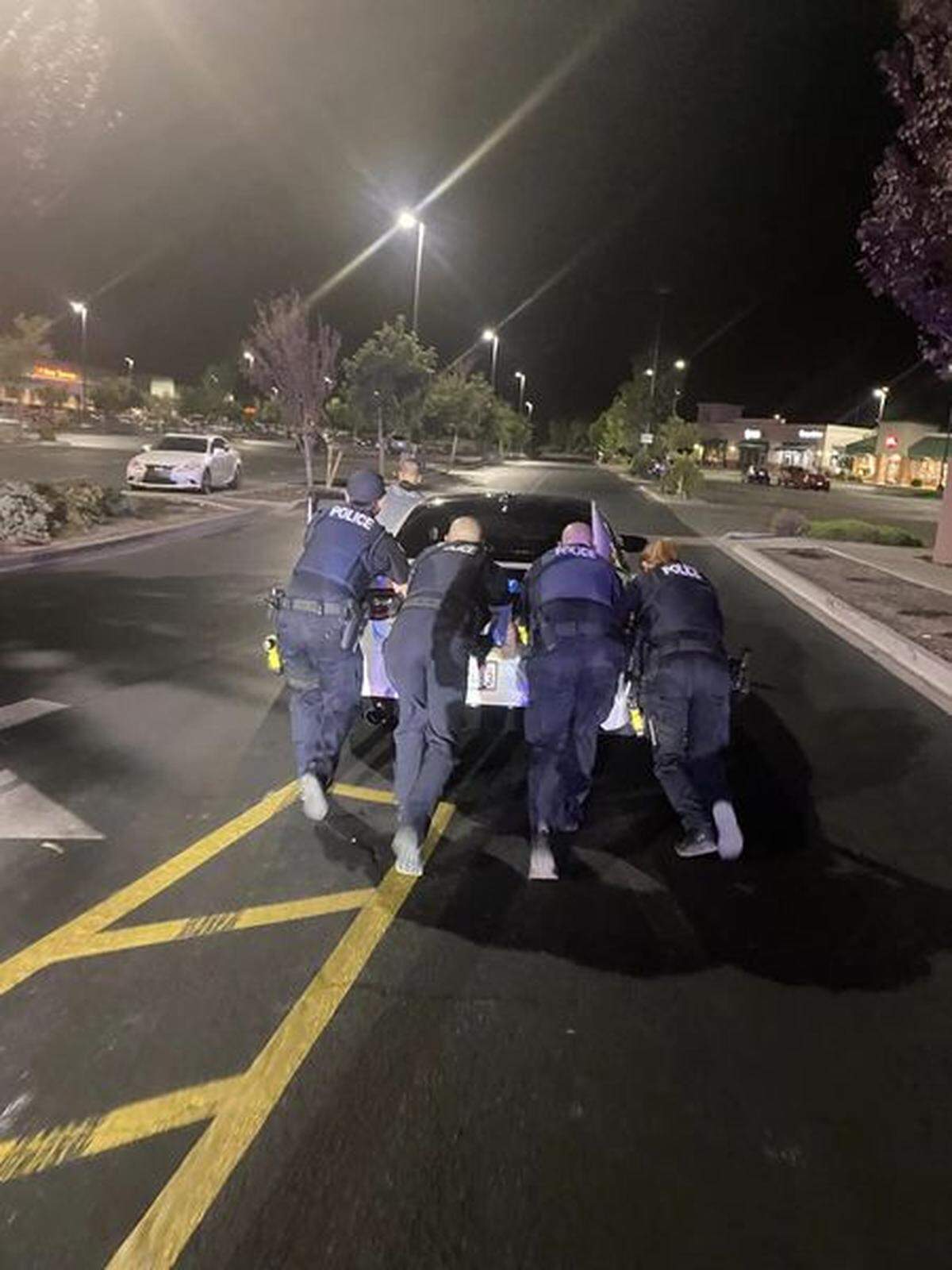 Richland police move a disabled Dodge Charger out of the line of traffic in the Richland Winco parking lot after spike strips were deployed in Interstate 182.