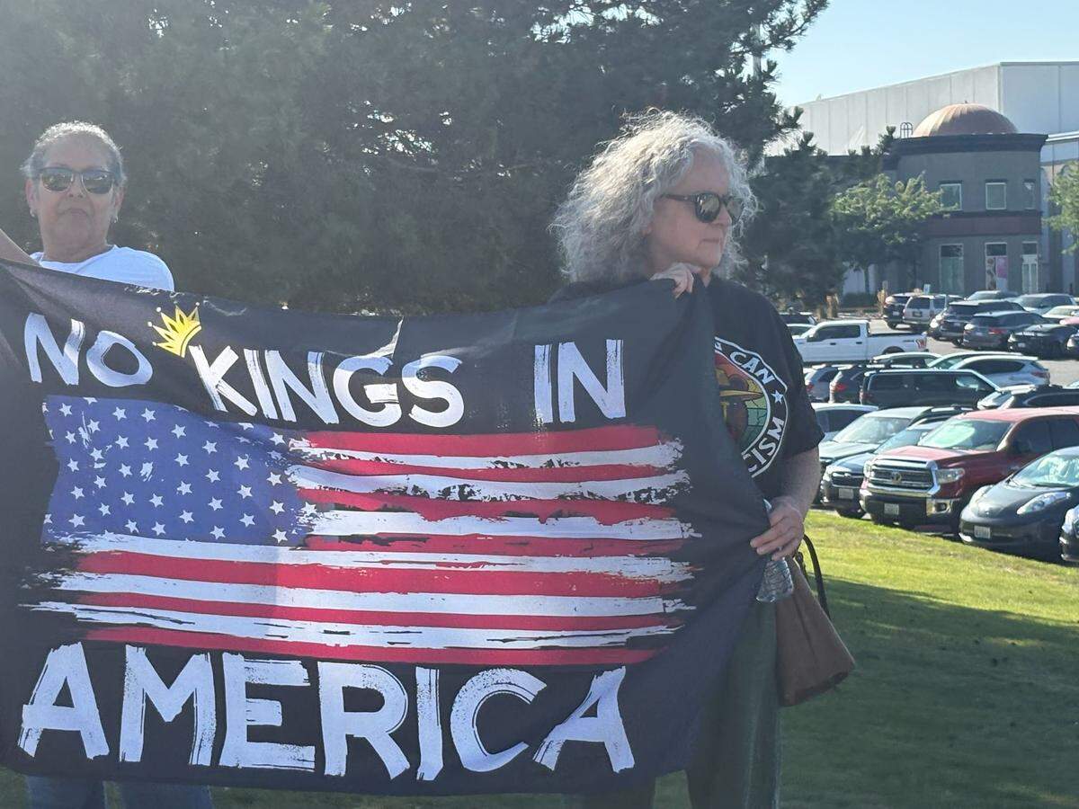 Protestors hold a flag reading “No Kings in America” near the entrance to one of the Columbia Center mall parking lots during the “Good Trouble Lives On” demonstration in Kennewick, Washington, on July 17, 2025.