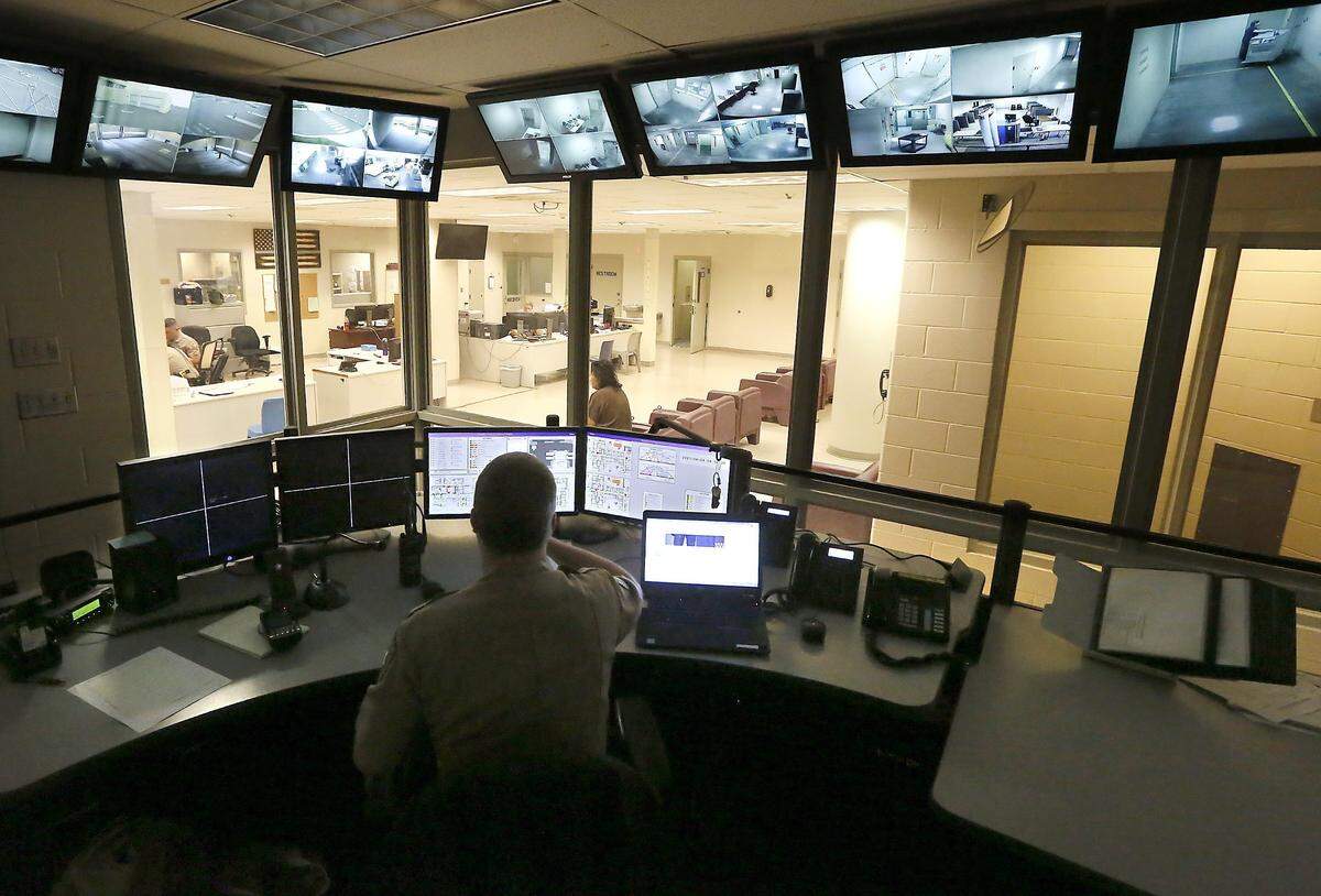 A Benton County Sheriff corrections officer monitors computer and video screens in the master control room near the booking area of the Benton County jail facility in Kennewick.