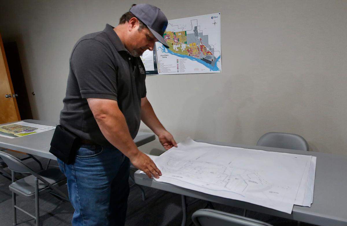James Sexton, owner of JMS Construction, leafs through drawings he submitted as part of the first phase of the Osprey Pointe development his company is working towards starting in Pasco.