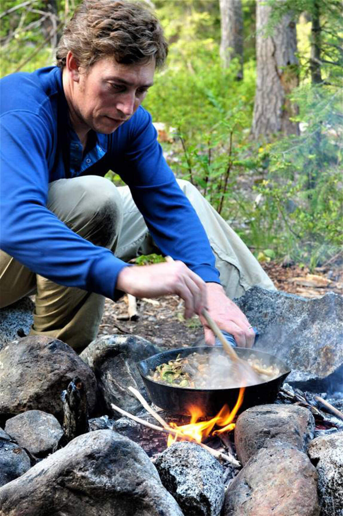 Langdon Cook cooking a wild edible food dinner over a camp fire.