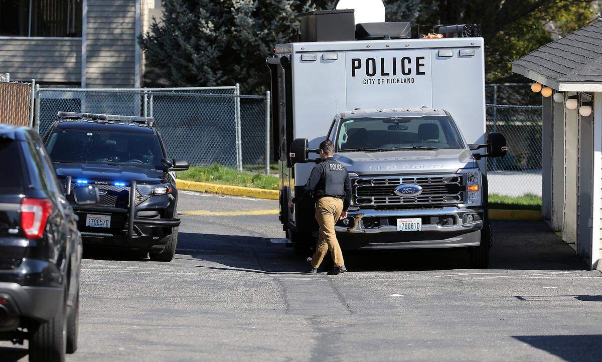 A Richalnd police investigator walks outside of building B at the Orchard Hills Apartment complex a 1845 Leslie Road in south Richland. Police responded to an early morning drive-by shooting at the site.