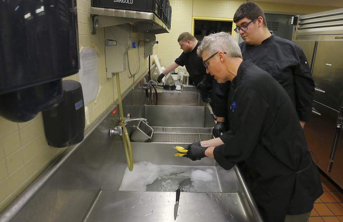 Chef Derek Smith instructs student Rafael Garcia on the proper and safe way to wash a knife during a lesson in the kitchen at the Opportunity Kitchen restaurant.