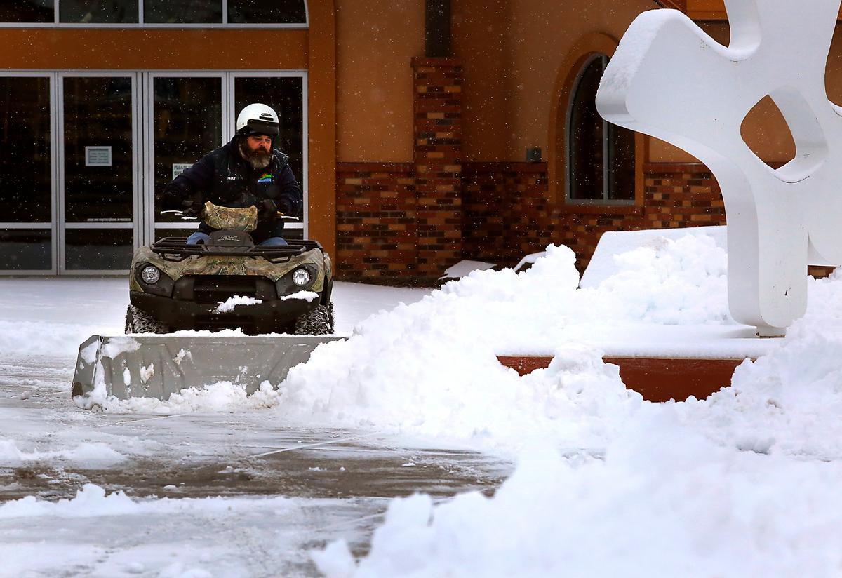 Paul Clements, a City of Kennewick employee, uses an ATV outfitted with a snow plow Monday morning to clear the walkways around the Southridge Sports & Events Complex.
