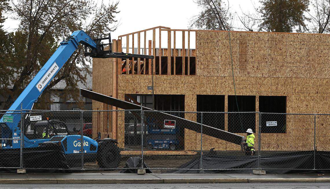 Construction workers prepare to lift a steel support beam into place for a new Panda Express restaurant in Pasco.