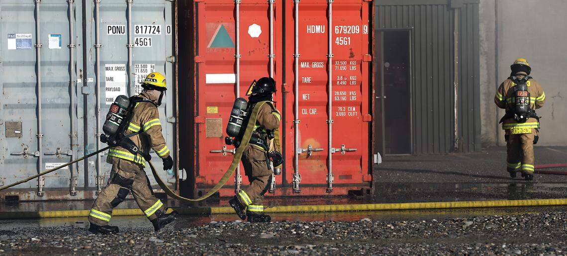 Firefighters carry hose as they work to extinguish an early morning warehouse fire on East Ainsworth Avenue in the Port of Pasco's Big Pasco Industrial Center.