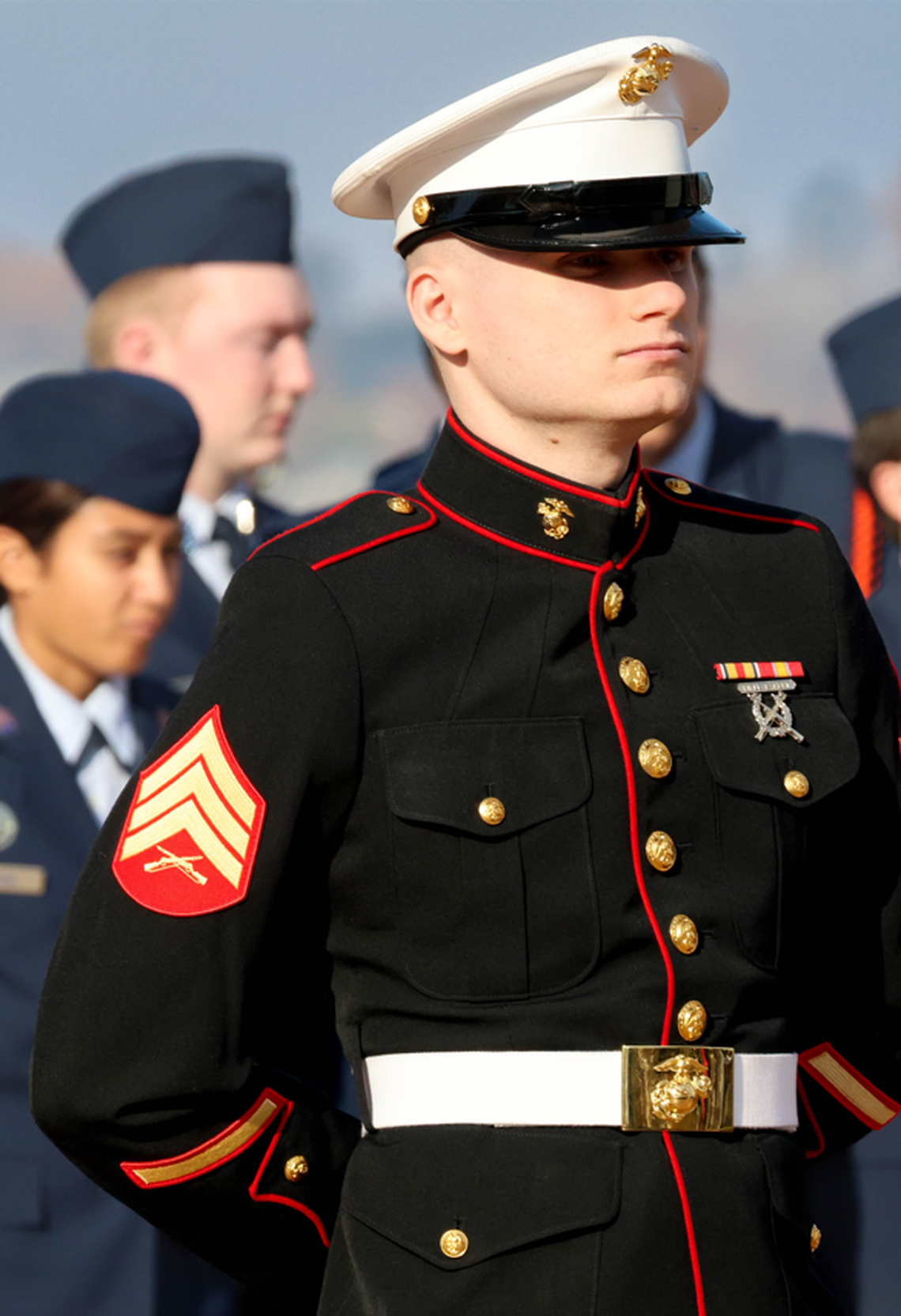 A U.S. Marine sergeant stands at attention during the Veterans Day ceremony at the memorial in Columbia Park on Monday. Behind him, members of the Kennewick High School Air Force Junior ROTC prepare for the flag presentation.