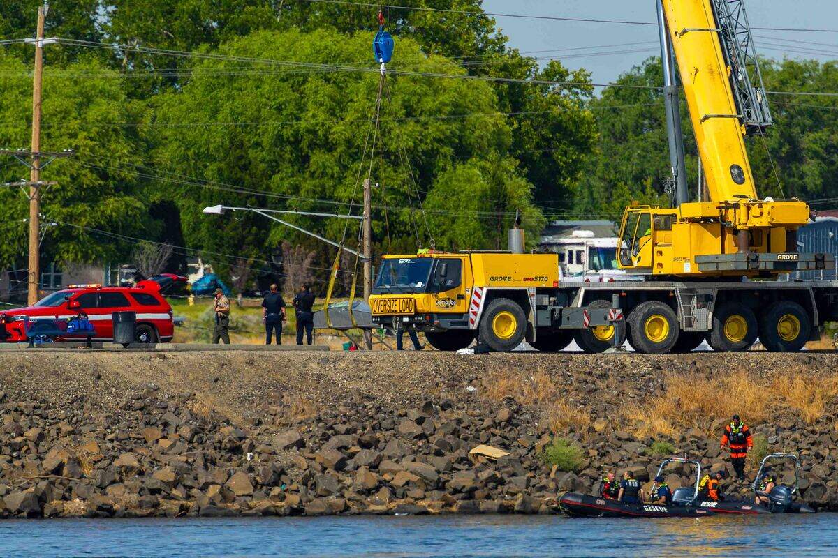 A crane on the Pasco shoreline pulls a floatplane that clipped and broke a power line over the Columbia River.