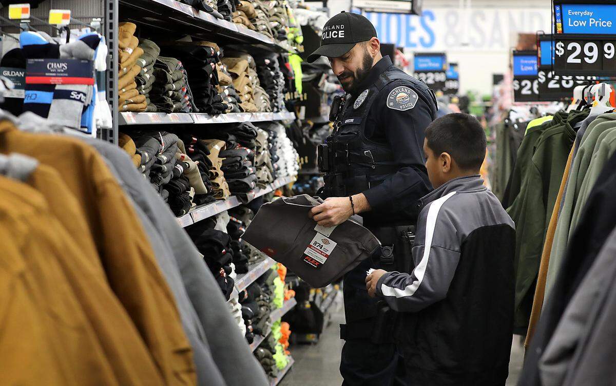 Richland Police Detective Christian Jabri helps Anthony Flores pick the correct size of pants during the annual Cops & Kids Christmas shopping event at the Richland Walmart store.