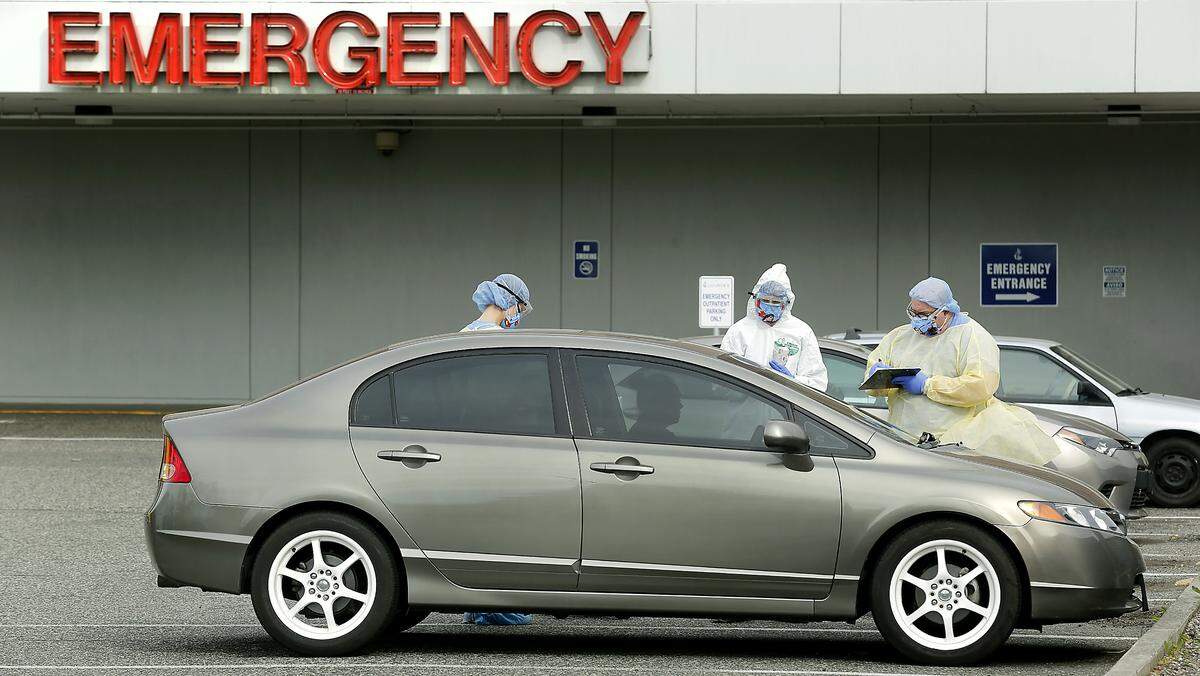 Medical workers dressed in protective equipment at Lourdes Health screen a woman in her car for signs or symptoms of coronavirus in the emergency room parking lot of the Pasco hospital before she enters the building. The screening is not a test for the virus. Watch a video at: tricityherald.com/videos