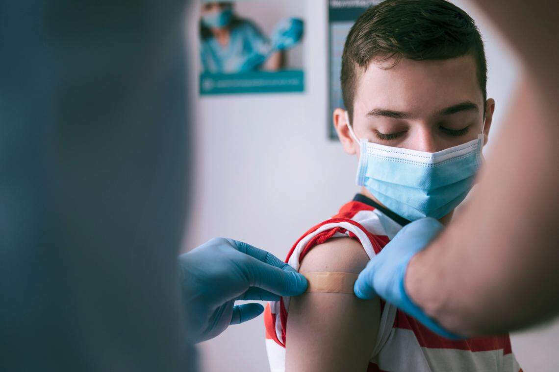 A teen boy gets an adhesive bandage on his arm after getting the Covid-19 vaccine.