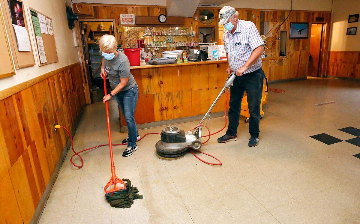 Bar manager Donna Totten, left, and club president Tom Throndsen work together cleaning and polishing the floors in the annex the private club has performed extensive cleaning and updating of their buildings during the shutdown because of the ongoing coronavirus pandemic. The club is close to reopening under the current modified plan in place in Benton County.