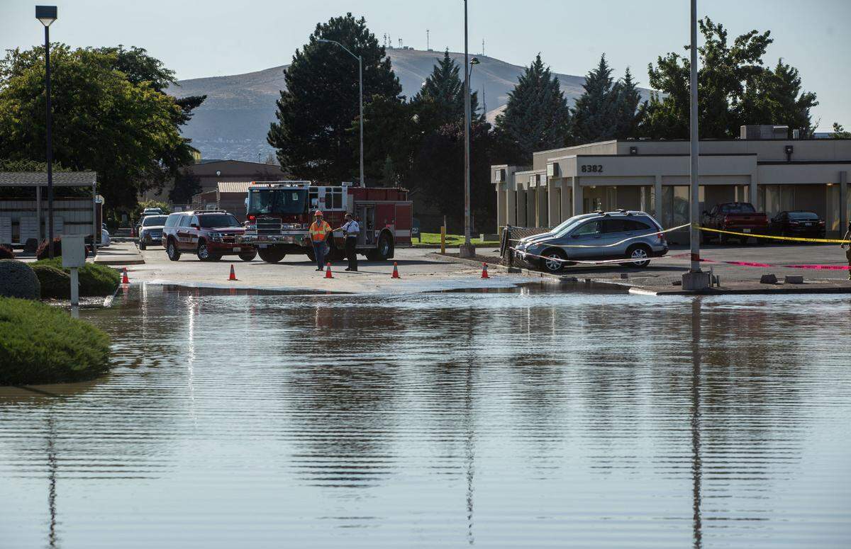 City workers and law enforcement officers block off roadways near Center Parkway and Gage Boulevard in Kennewick after a 10-inch water main broke around 4 p.m., causing the area to flood.