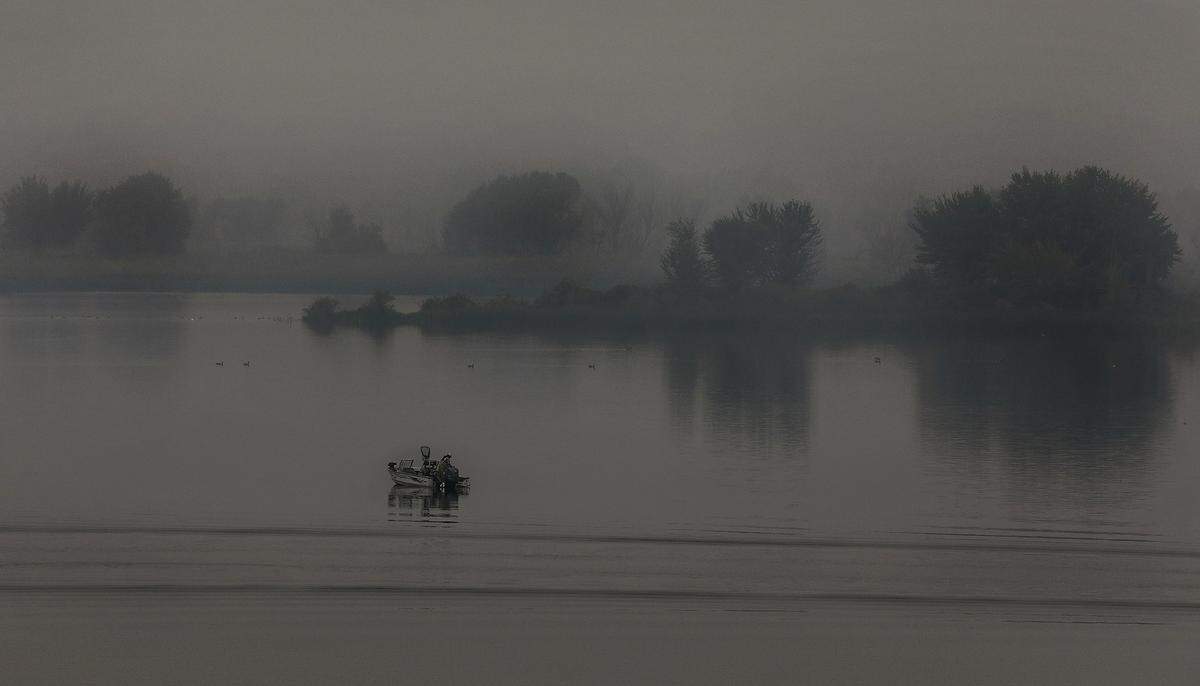 Thick stagnant air filled with wildfire smoke reduces visibility early Monday morning for this angler trolling on the Columbia River near the confluence with the Yakima River.