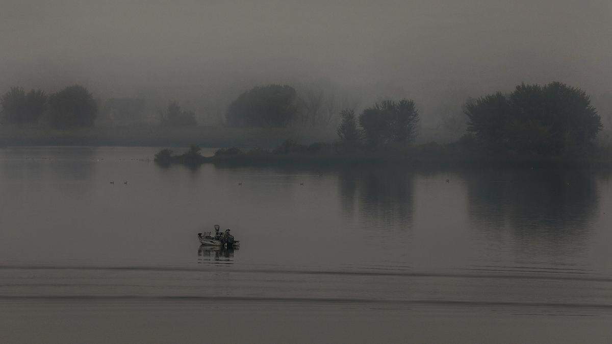 Thick stagnant air filled with wildfire smoke reduces visibility early Monday morning for this angler trolling on the Columbia River near the confluence with the Yakima River.