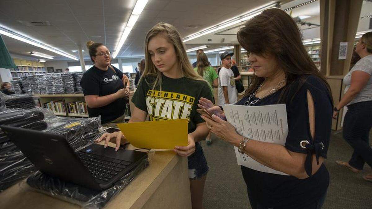 Richland Bomber sophomore Natasha Ford, checks her new Google Chrome book is working properly with her mother, Darla Ford, during registration at Richland High School.