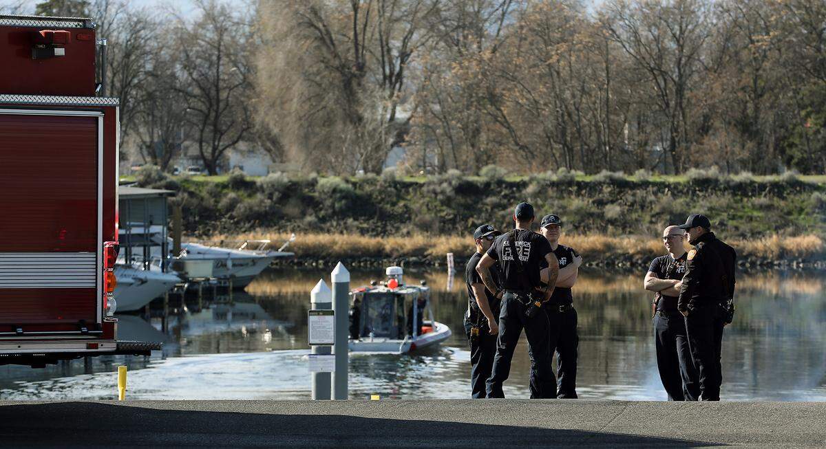 Kenenwick firefighters stand at the boat launch on Clover Island after responding to a water rescue on the Columbia River near the cable bridge.