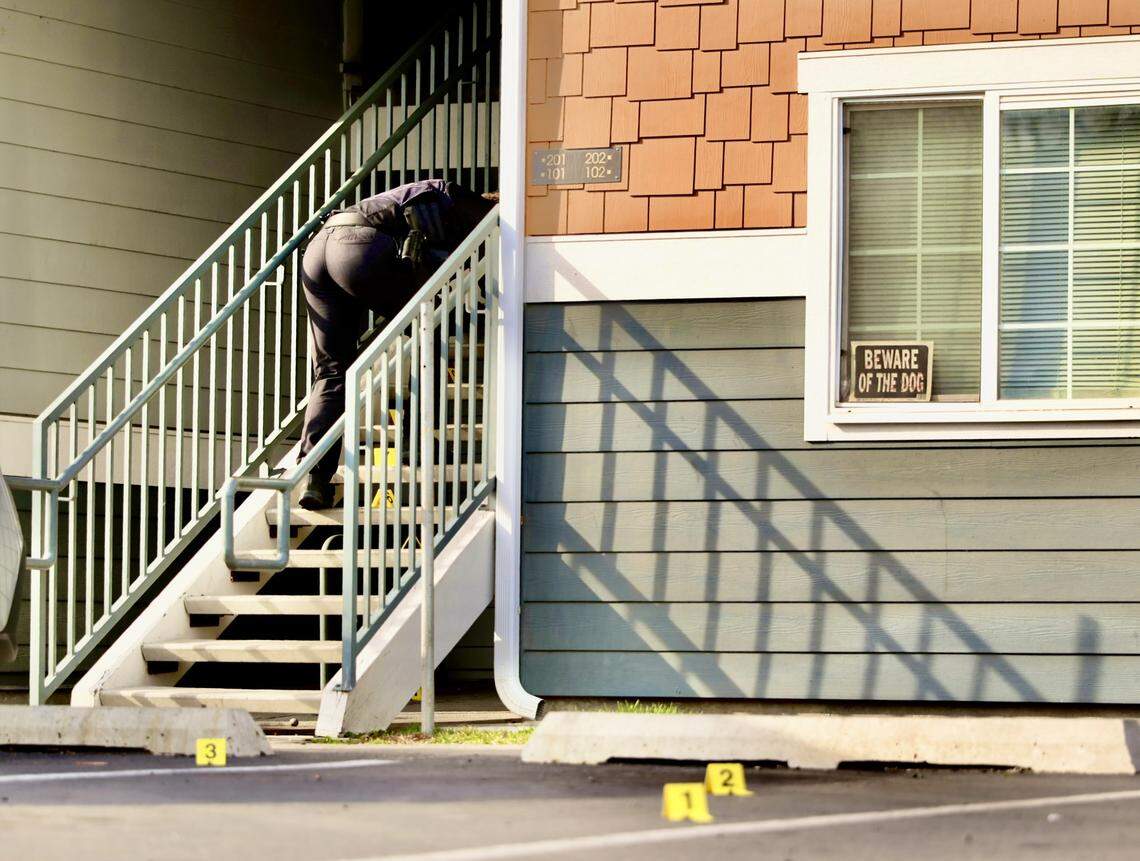 A Kennewick police officer collects evidence on the steps of the Heatherstone Apartments on Sunday afternoon.