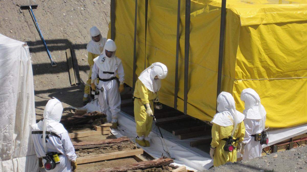 Hanford workers check beneath a box of suspected transuranic waste they were preparing to move from temporary underground storage in 2010. The box was covered and lifted onto a base that supported the underside of the damaged container.