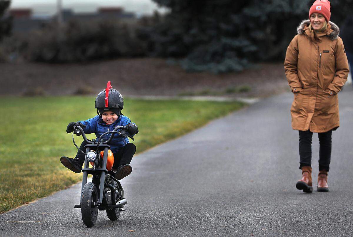 Three-year-old Cristiano Perez adds pizzazz to his riding style while zooming along the pathway on his battery-powered toy motorcycle in Claybell Park during a morning trek with his mother, Vanessa Perez, in south Richland.