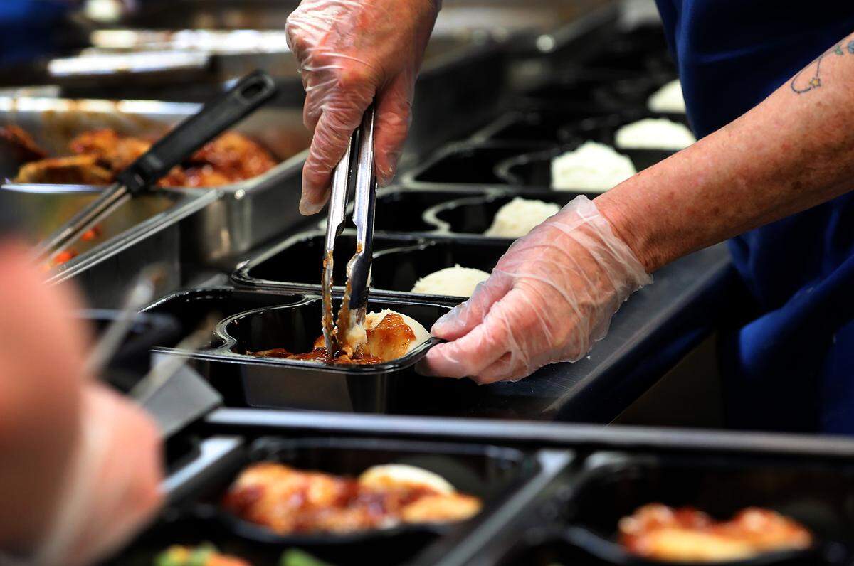 Volunteer Josie Beach helps a team of volunteers and staff fill over 300 trays of meals for seniors through the Mid-Columbia Meals on Wheels program.