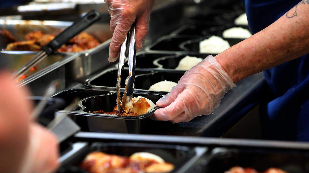Volunteer Josie Beach helps a team of volunteers and staff fill over 300 trays of fresh cooked meals that were to be frozen and then later delivered to area senior citizens through the Mid-Columbia Meals on Wheels program.