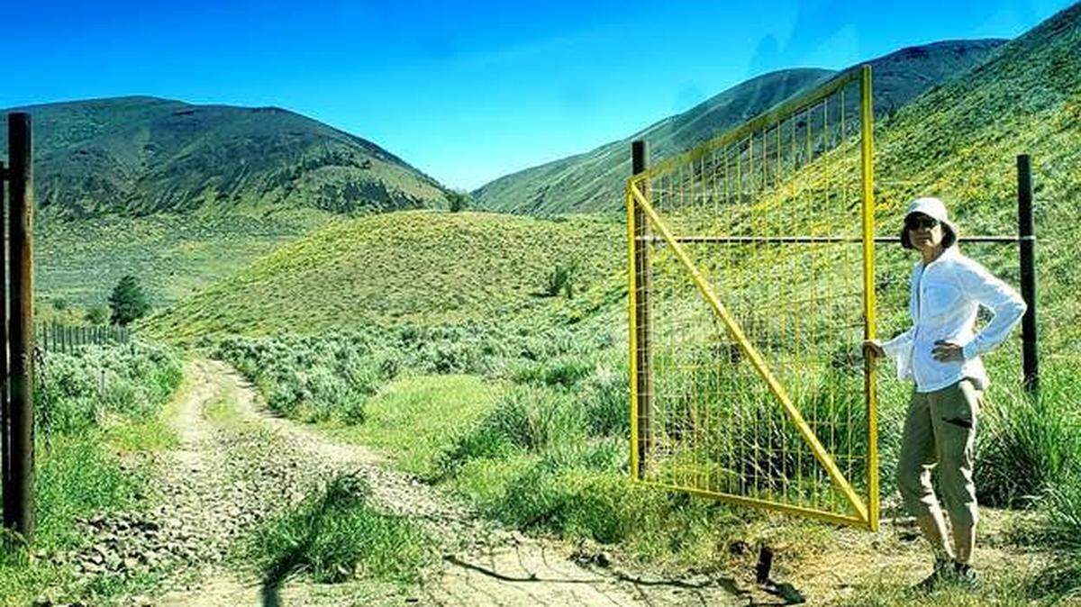 Nancy Krupin, president of the Inter-Mountain Alpine Club, holds open the entrance gate to Black Canyon Trail on Umtanum Ridge north of Yakima.
