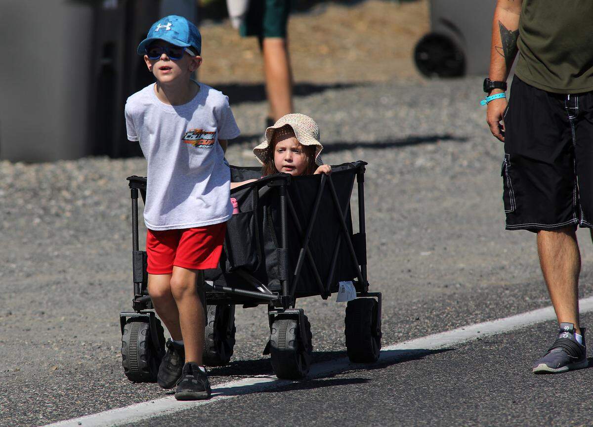 Young race fan is pulled in a wagon by a sibling as they make their way through Columbia Park during the second day of racing action at the Columbia Cup and STCU Over the River Air Show in the Tri-Cities. 