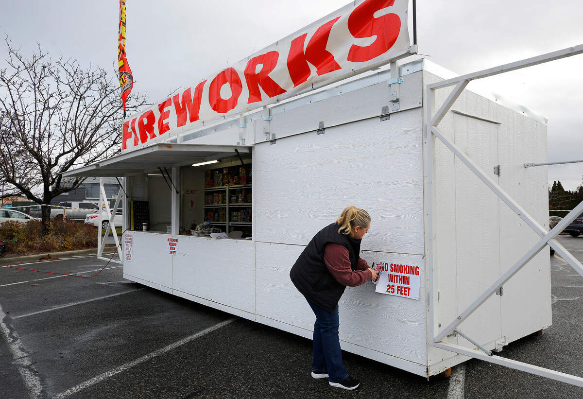 Kirstin Thompson staples warning signs on her family run fireworks stand in the parking lot of the Pasco Walmart. She was preparing to open the sales stand in preparation for New Year’s sales schedule.