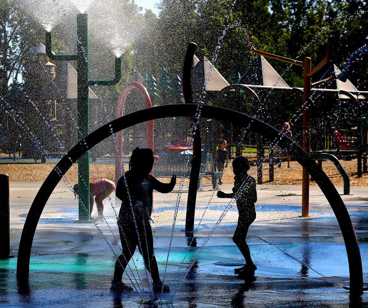 Children play in the shaded area of the splash park near the Playground of Dreams early Thursday. More hot, sunny and summer weather is forecast by the National Weather Service next week, including for Columbia Cup hydroplane racing events.