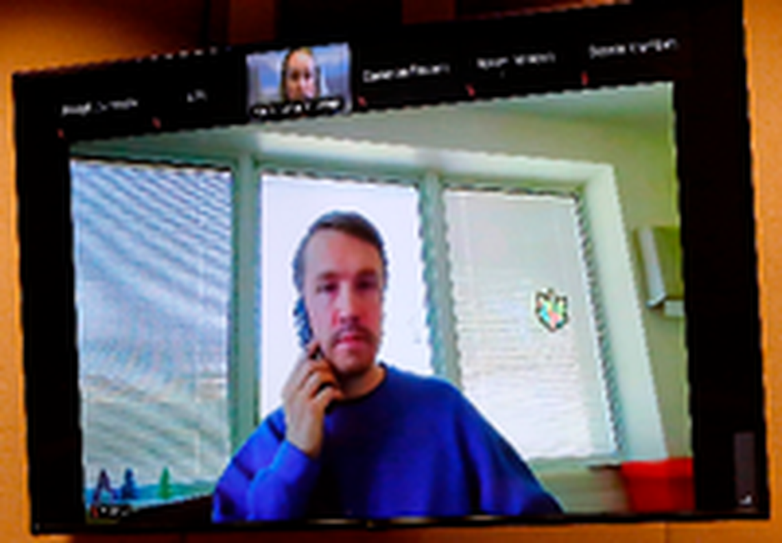 Aaron Kelly, who is accused of shooting two men inside the Richland Fred Meyer store in February 2022, uses a cellphone to privately talk with his defense attorneys during Tuesday’s hearing.