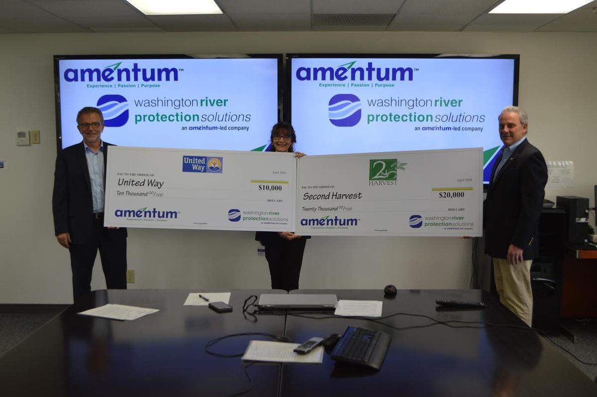 Bruce Covert, left, Amentum senior vice presdent of operations at the Hanford vitrification plant; LoAnn Ayers, president of United Way of Benton and Franklin Counties; and John Eschenberg, right, president of Hanford contractor Washington River Protection Solutions, show checks donated by Amentum and its Hanford companies to United Way and Second Harvest on Thursday.