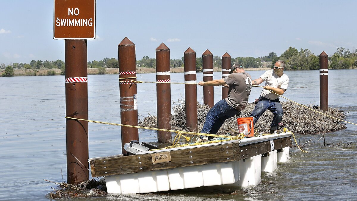 Kevin Vendeland, left, and Corey Nunn, with Marine Floats in Tacoma, strain to overcome a strong current in the Columbia River as they pull a section of a new floating dock into place against pilings Tuesday at the Two Rivers Park boat launch in Finley. The Benton County Parks Department launch is closed through May 18.