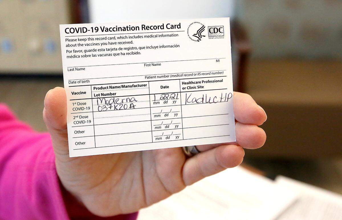 A Kadlec employee holds up a vaccination record card at a COVID-19 community vaccination clinic held at the Kadlec Healthplex facility in Richland.
