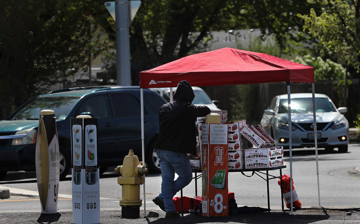 A roadside fruit vendor stands under a canopy at the roundabout at the intersection of West Fourth Avenue and South Union Street in Kennewick.