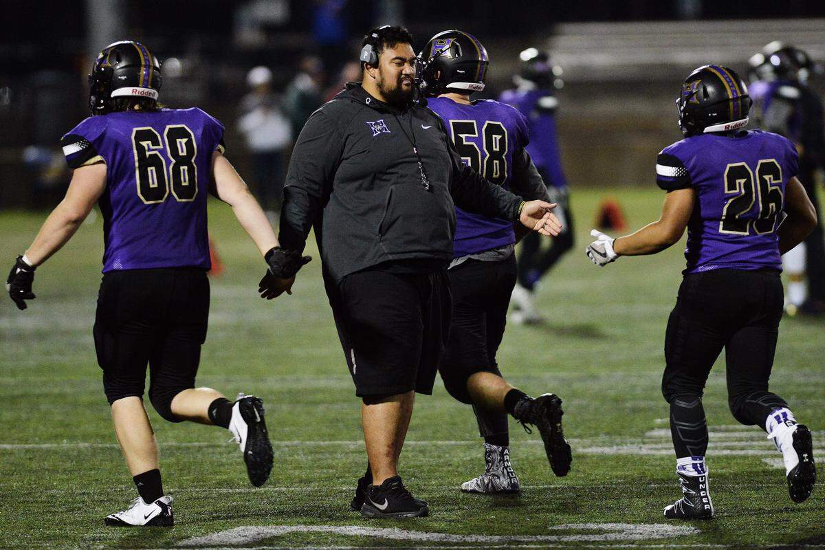 Hermiston coach David Faaeteete (center) congratulates players coming off the field after the Bulldogs’ 38-35 win over Churchill in the Oregon Class 5A state championship game in November.