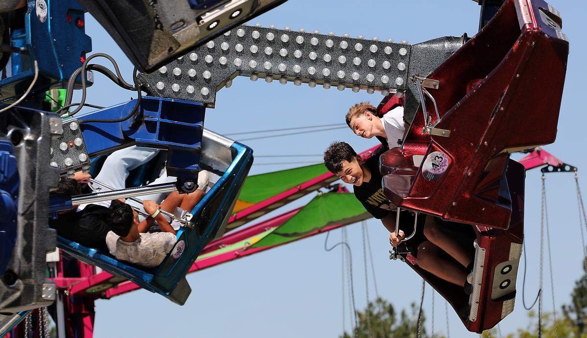 Riders on the fast-paced Orbiter wear contrasting faces of emotion in the Davis Shows Northwest carnival area at the Benton Franklin Fair & Rodeo in Kennewick.
