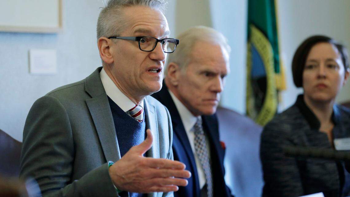 John Wiesman, left, Washington State Secretary of Health, talks to reporters Feb. 8 following a public hearing before the House Health Care & Wellness Committee at the Capitol in Olympia. A measles outbreak that has sickened at least 63 people has now cost the state more than $1 million. (AP Photo/Ted S. Warren)