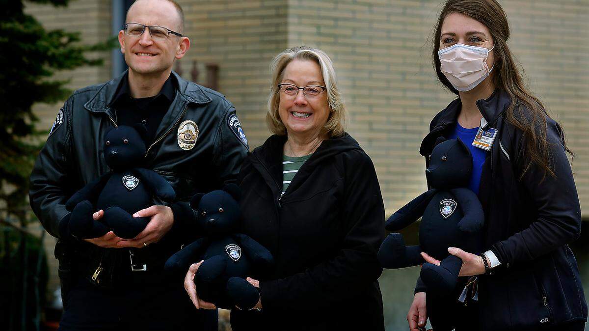 Sgt. Chris Littrell, CHIPS volunteer Annette Kuhl, and Kadlec Child Life Specialist Jenny Jones, from left, share a smile during a presentation Tuesday morning of stuffed bears made from previously worn police uniforms to the Richland hospital. The CHIPS volunteers sew the bears and attach a special badge to them to be distributed to children battling health issues.
