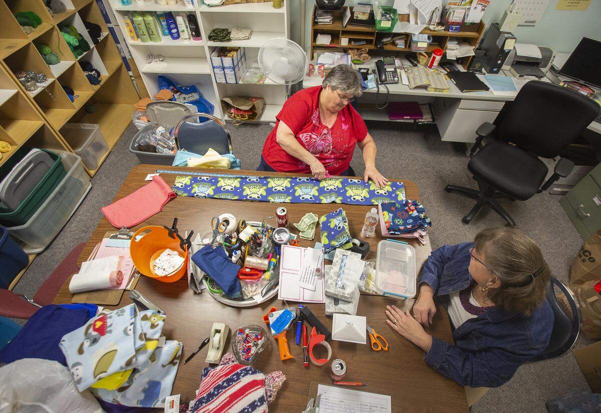 Volunteers make scarves inside Project Warm-Up headquarters at Community Action Connections in Pasco on Tuesday. 