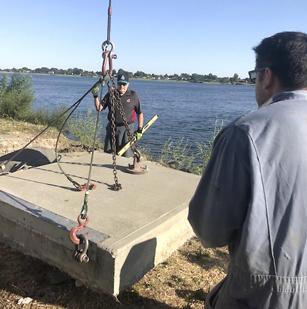 Volunteer Clarence Martin, 76, signals to a crane operator recently while working on relocating a concrete pad used to attach walkways for floating docks used in the upcoming Tri-Cities Water Follies boat racing event in Columbia Park.