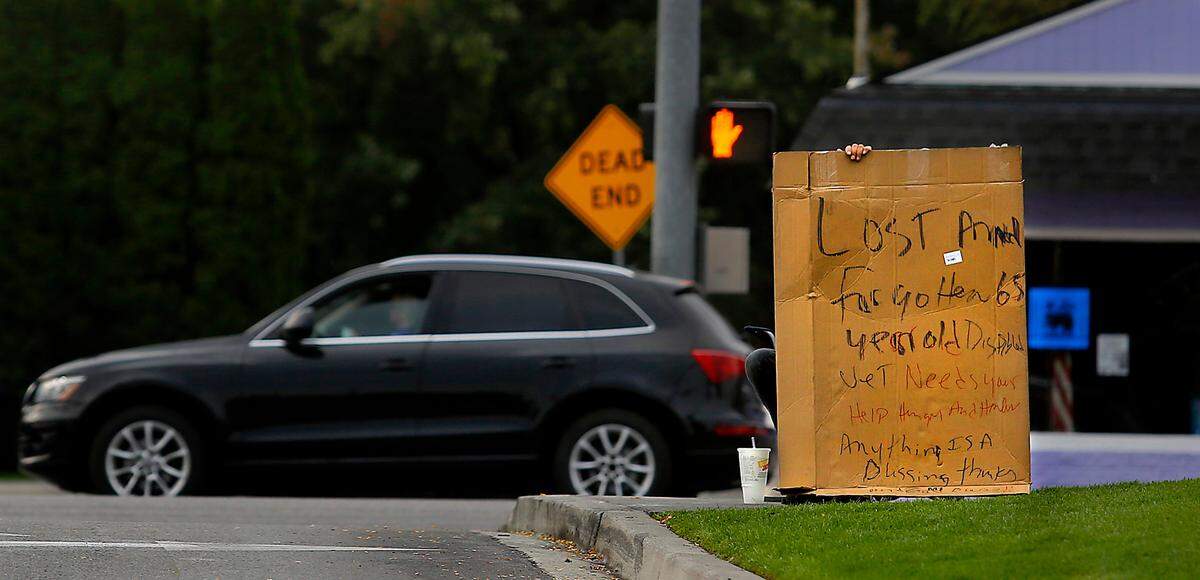 A homeless man holds a sign in September 2022 at the entrance to the WinCo grocery store on West Clearwater Avenue in Kennewick.